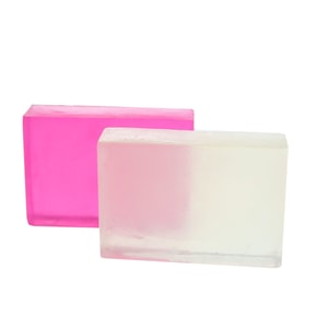 Two rectangular blocks of translucent melt and pour soap standing upright; one is vibrant pink and the other is the uncolored clear base with a slight yellow tint.