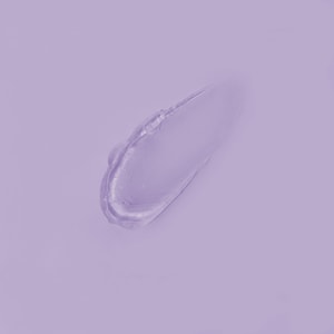 A top-down close-up of a smooth, perfectly transparent swatch of clear hair pomade resting gracefully on a solid light purple surface.