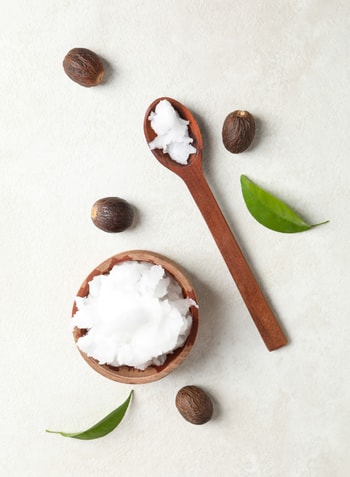 Liquid coconut oil in glass jar, broken coconuts, dark table, se