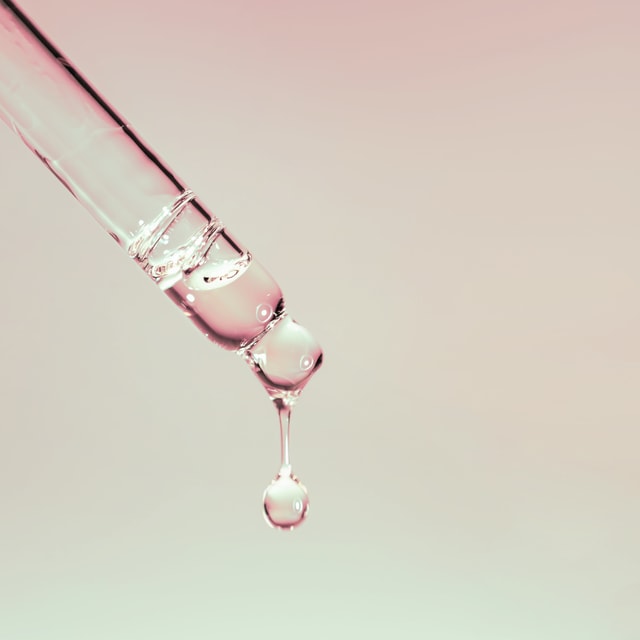 A drop of cosmetic oil falls from the pipette